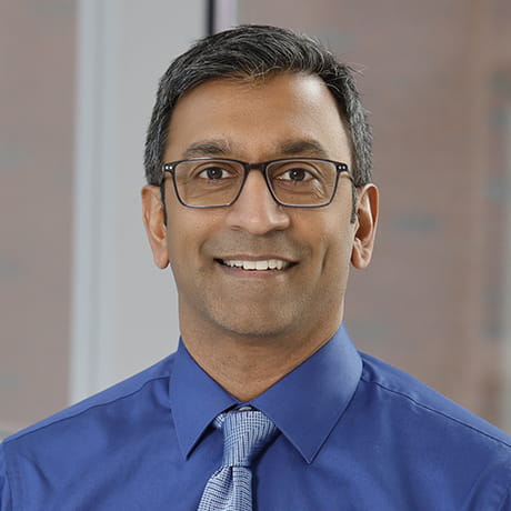 Headshot of Ajit smiling wearing blue shirt 
