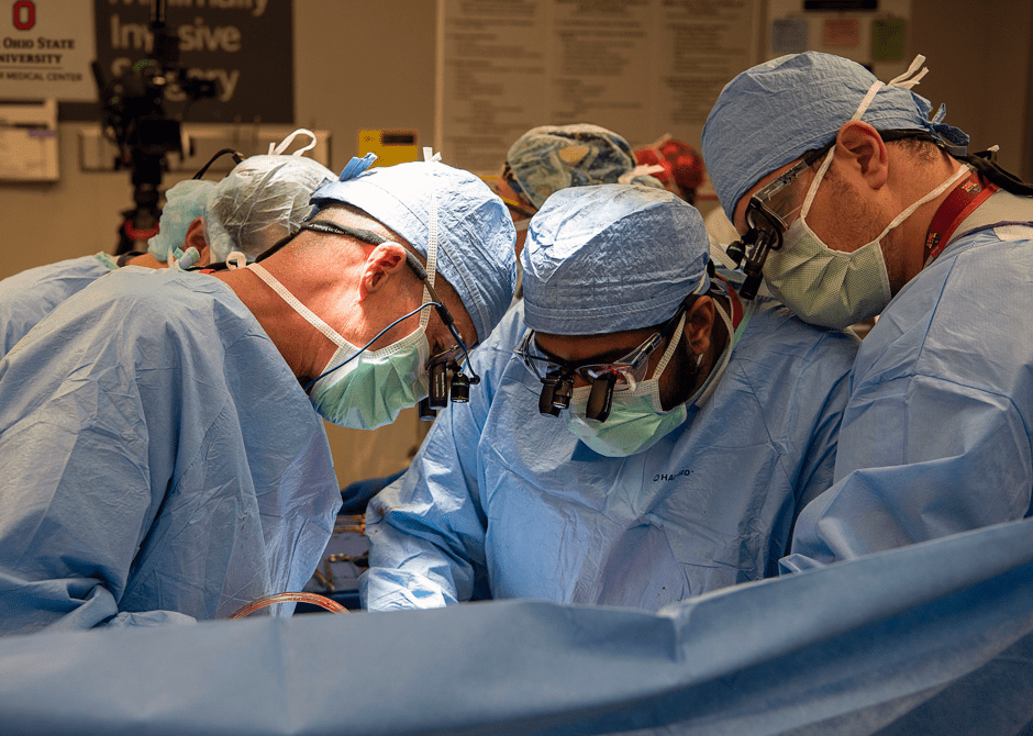 Dr. Ken Washburn (left) performing transplant surgery with two fellows assisting