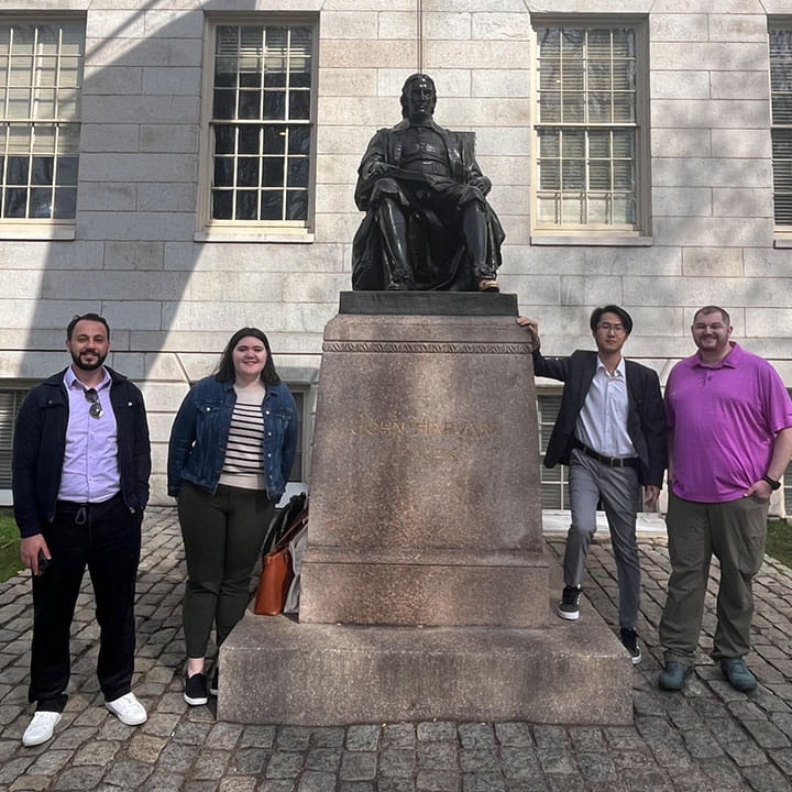 Four students standing around a statue. 