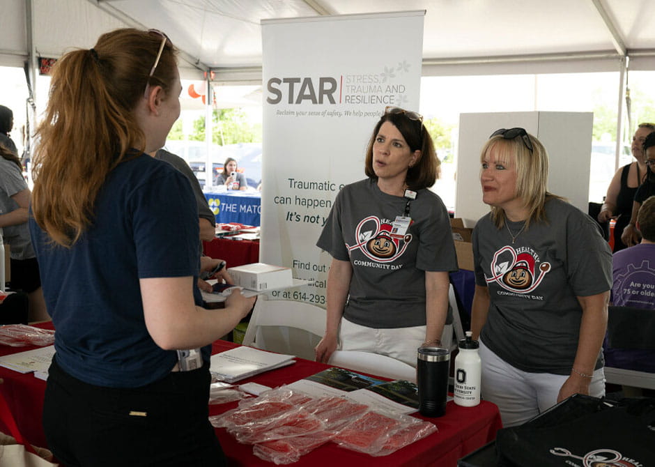 two women behind a table talking to another woman about the STAR program.