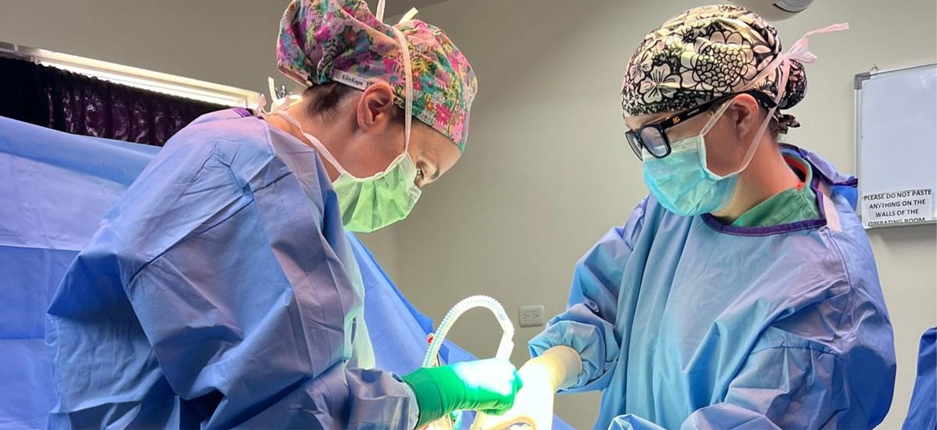 Two surgeons in scrubs perform surgery.