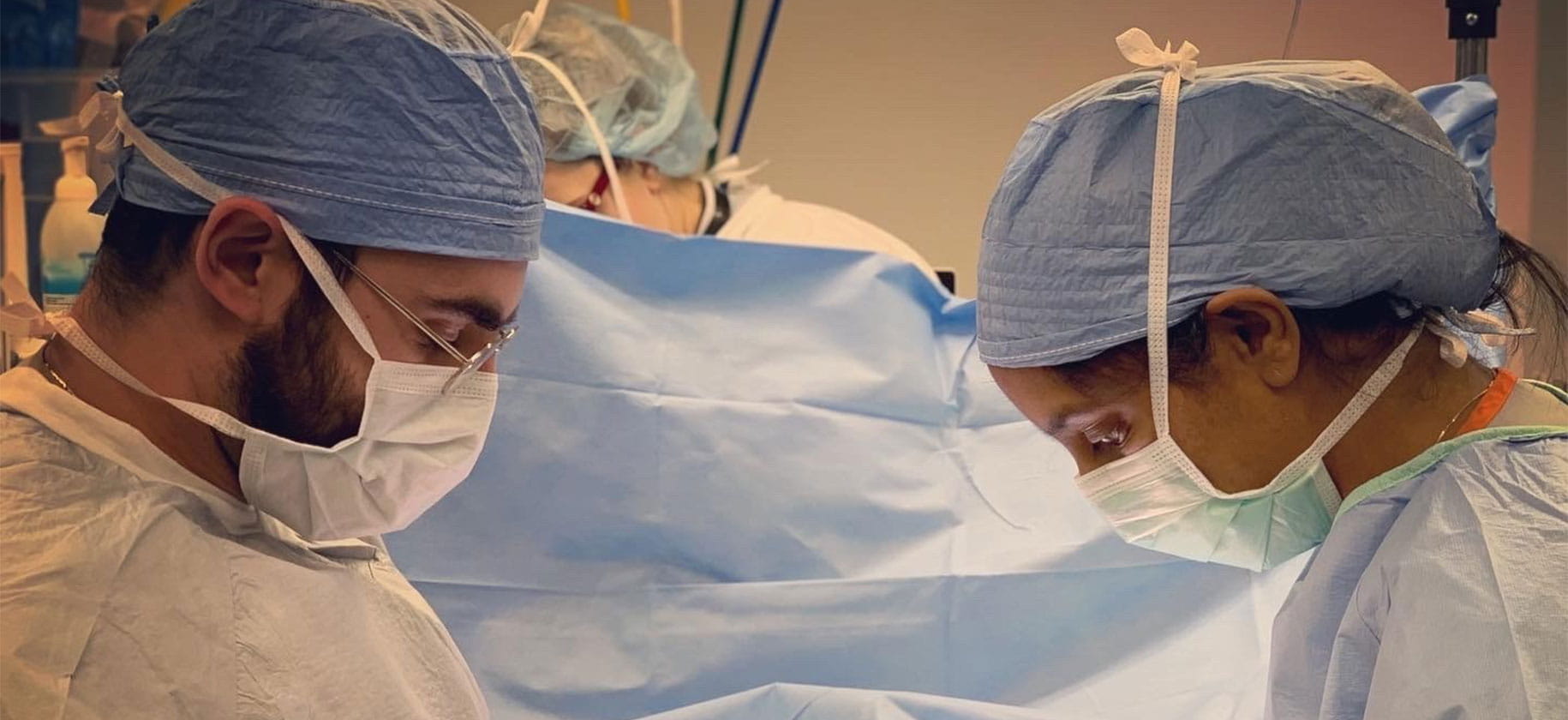 Two surgeons in scrubs perform surgery.