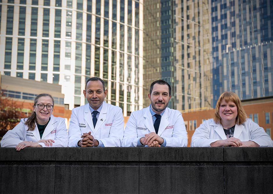 four people in white coats leaning against a wall