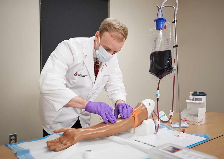 Medical student Jordan Lukens practicing medicine on a plastic arm