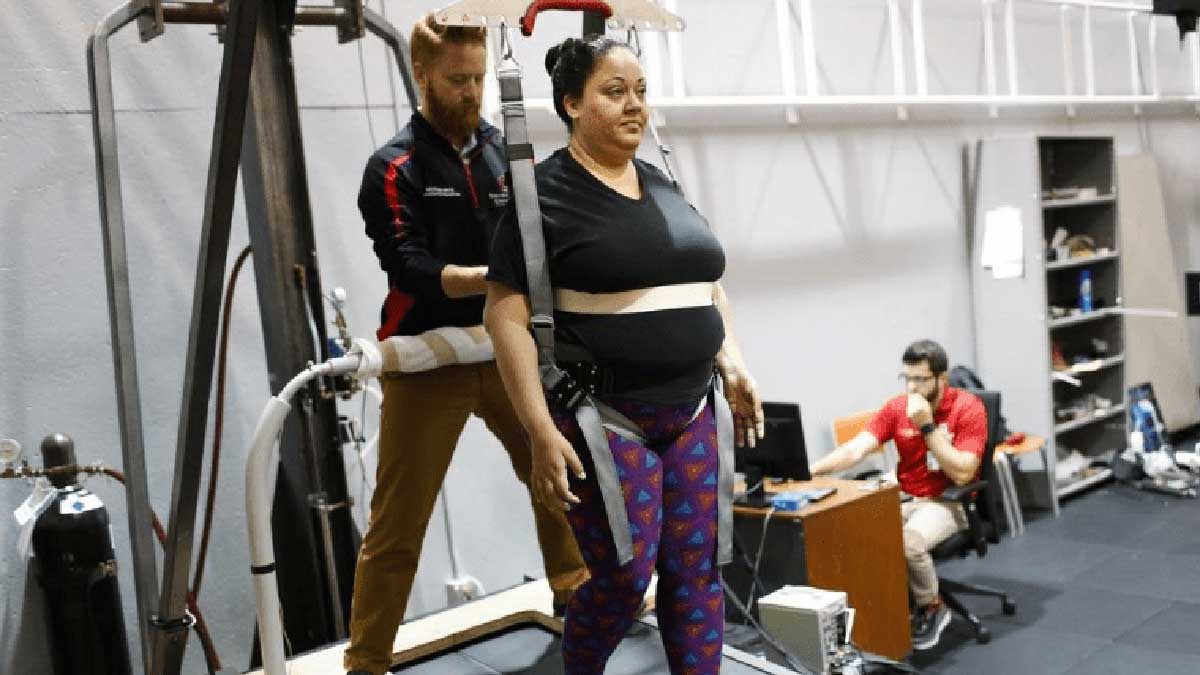 Woman on treadmill assisted by rehabilitation therapist