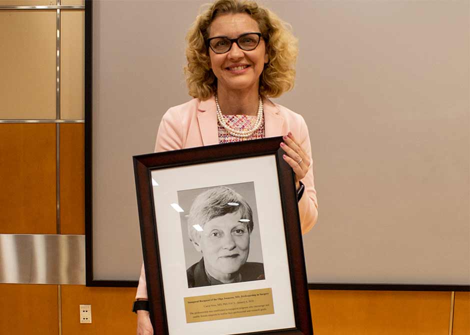 Dr. Sims holding a portrait of Dr. Jonasson