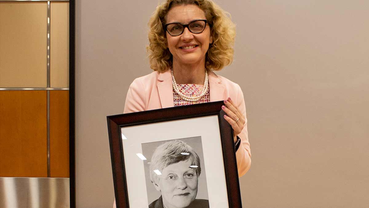 Dr. Carrie Sims holding a portrait of Dr. Olga Jonasson