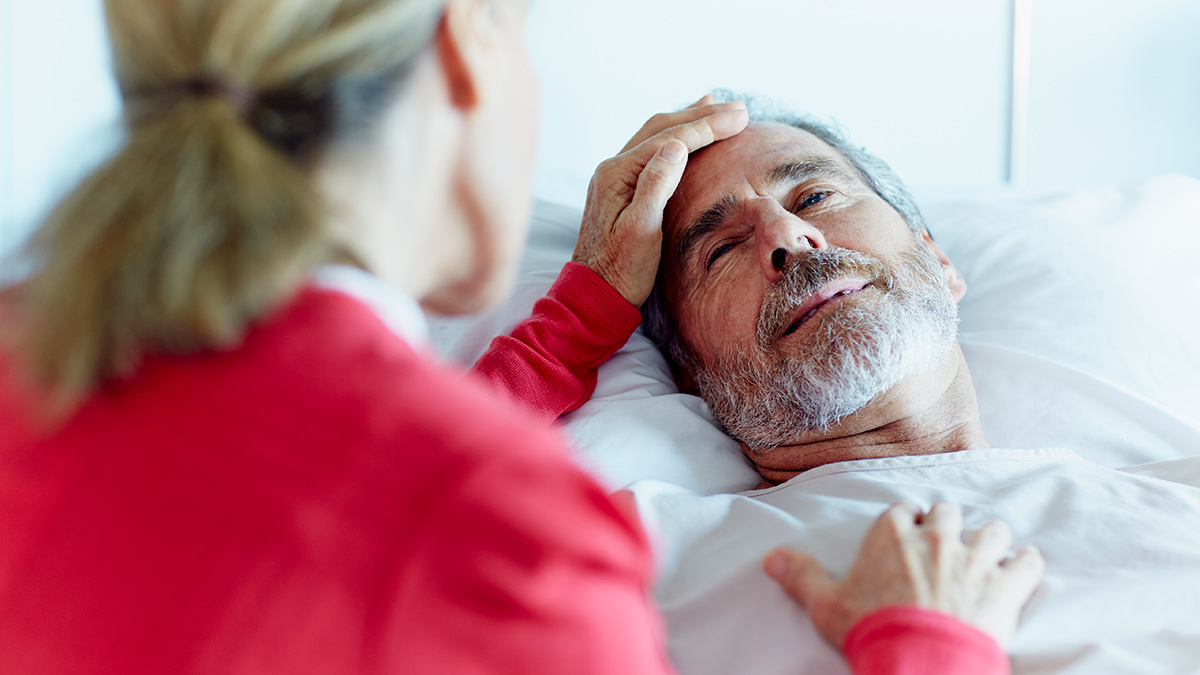 Woman caressing a man laying in a hospital bed