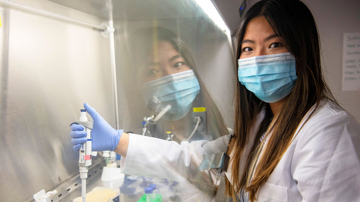 A female PhD in immunology student using a pipet in the lab