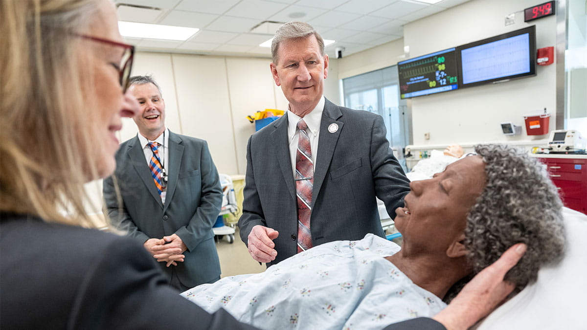 The Ohio State University President Ted Carter and College of Medicine Dean Carol Bradford interact with a dummy patient.