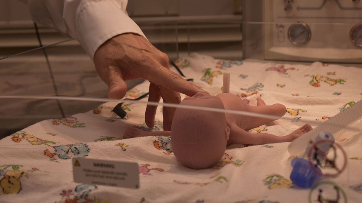 Hand touching a baby mannequin 