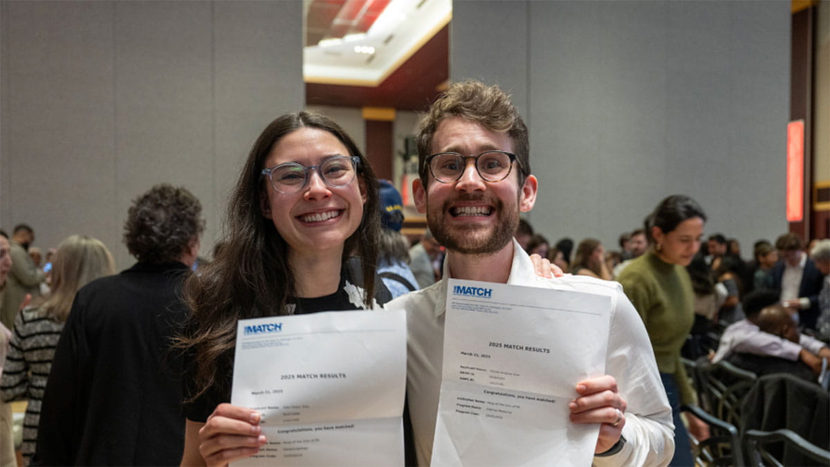 Two people holding up their papers showing that they have matched