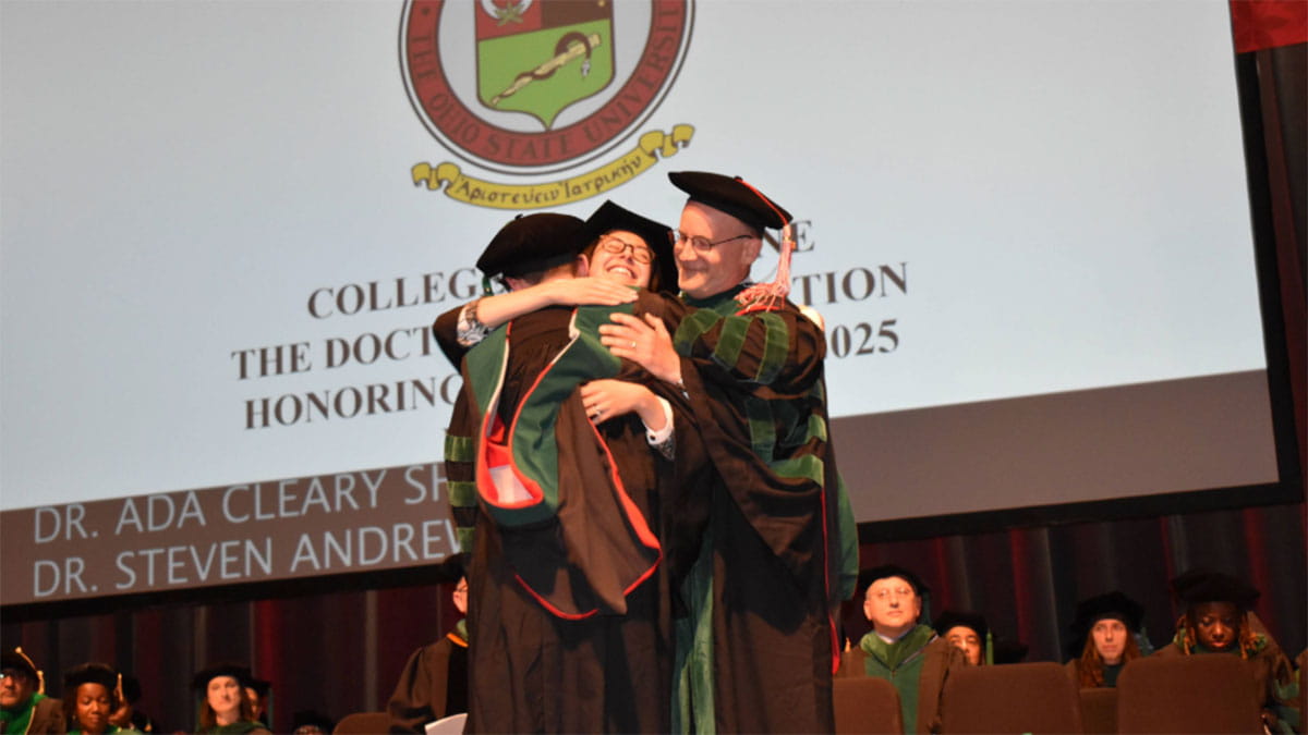 A medical student hugging two faculty members.