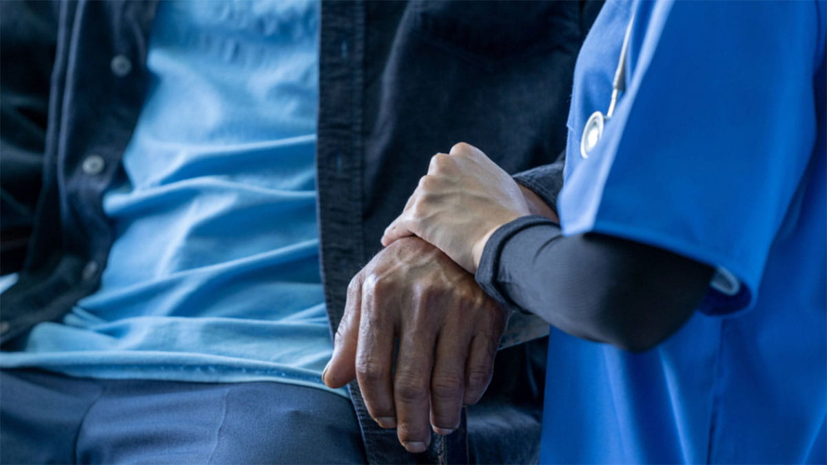 Image of a nurse holding a person's hand.