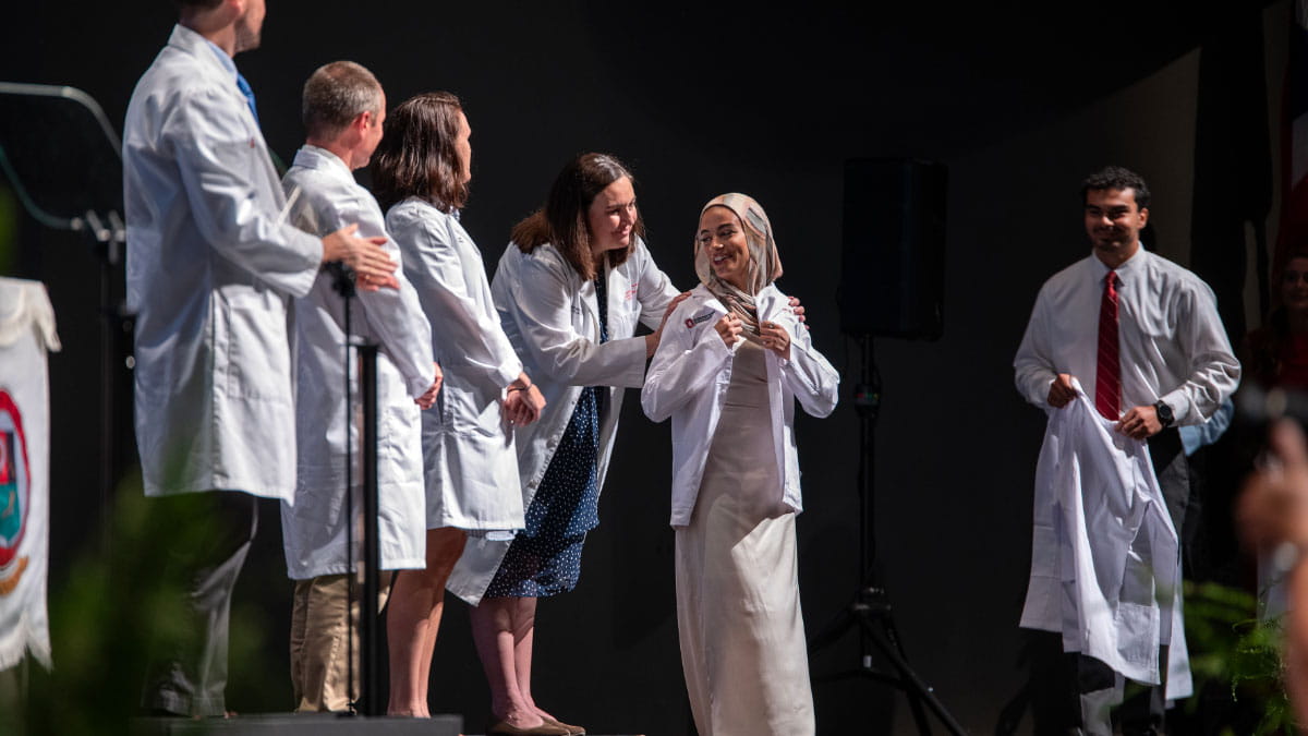 Image of a student putting on their white coat