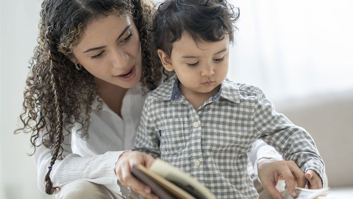 A woman and a young child read a book together.