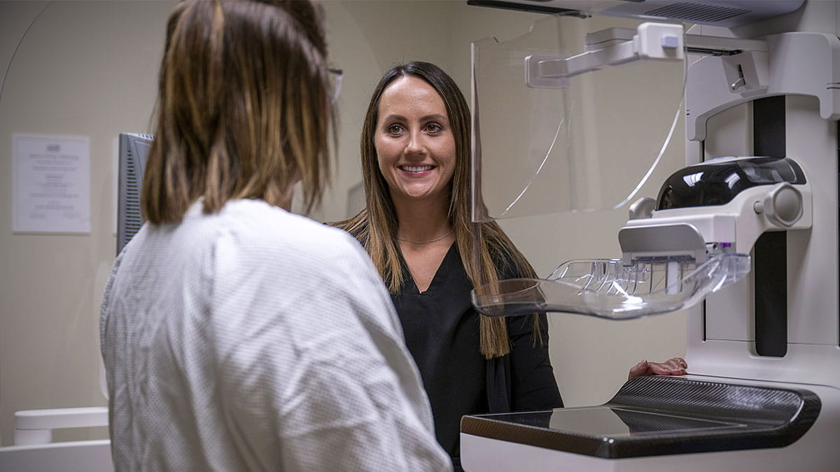 A person in a white coat talking to a person in a medical office.
