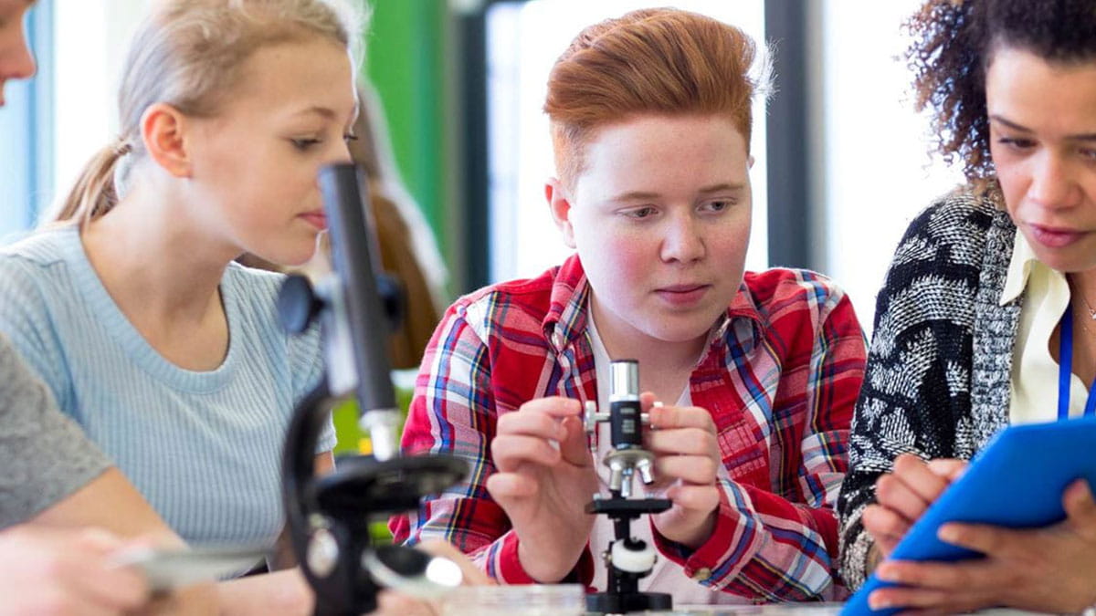 Students gathered around a microscope, engaging in a science activity.