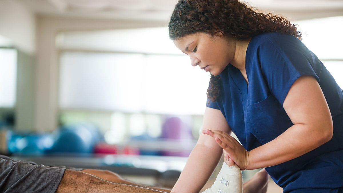 A physical therapist uses their hands to work with a patient. 