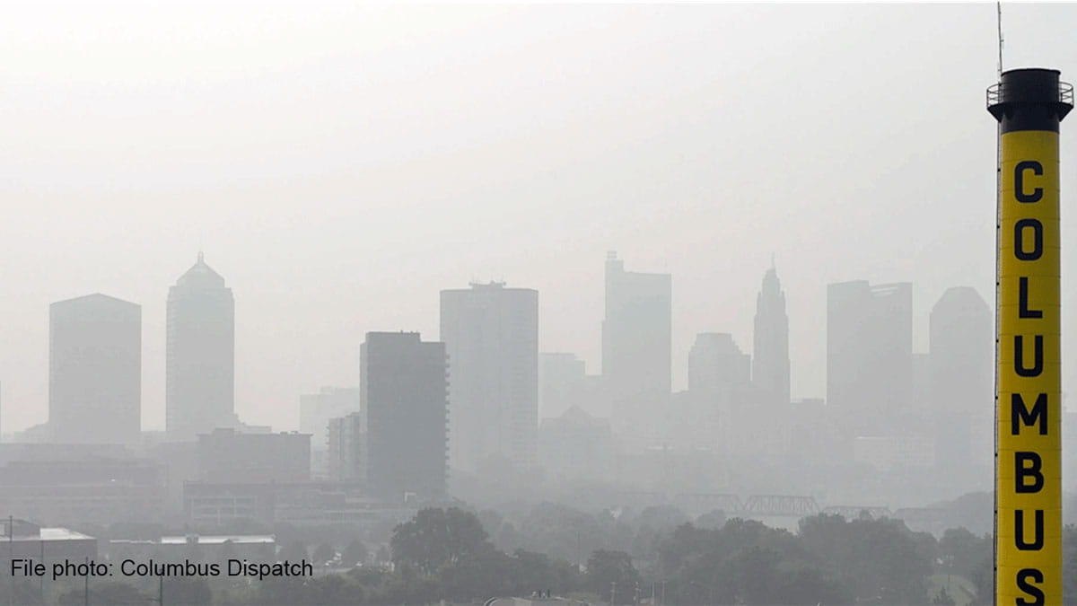 A hazy city skyline with various building shapes in muted colors, featuring a prominent yellow structure labeled "COLUMBUS" on the right.