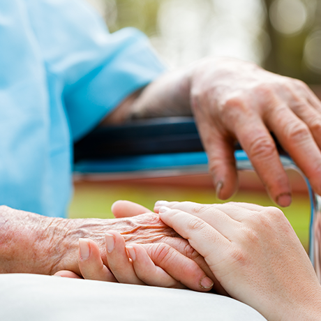 Seated elderly man holding the hands of a younger woman