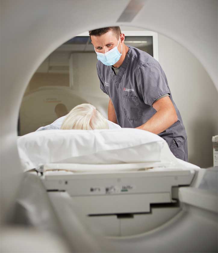 Patient about to receive MRI assisted by provider wearing face mask