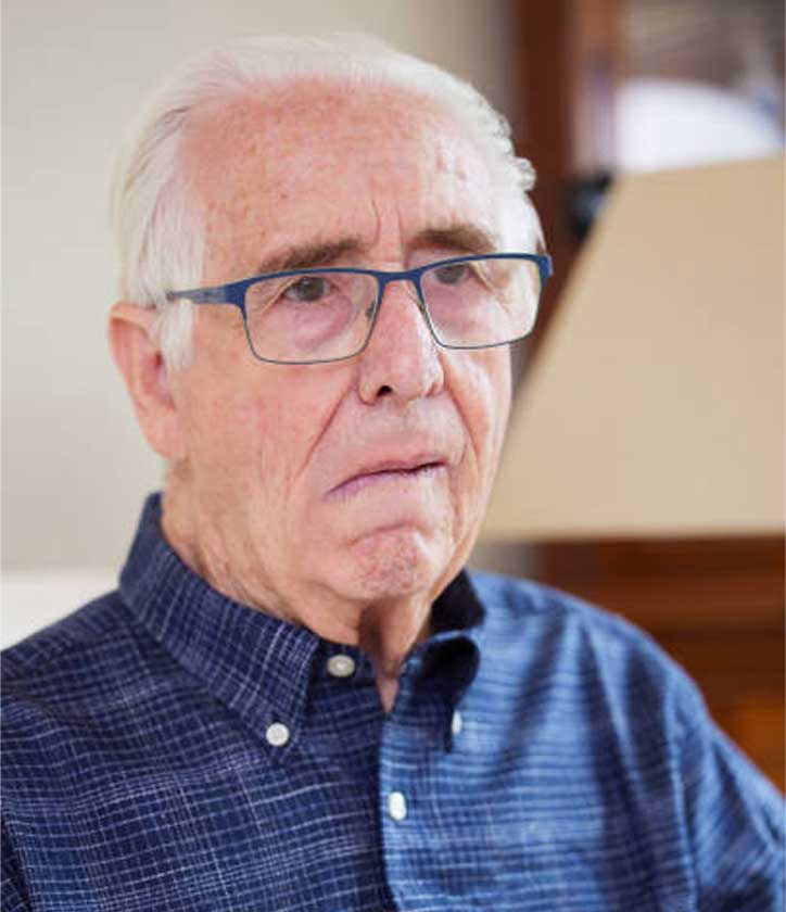 Senior man at home suffering from side effects of stroke showing face drooping