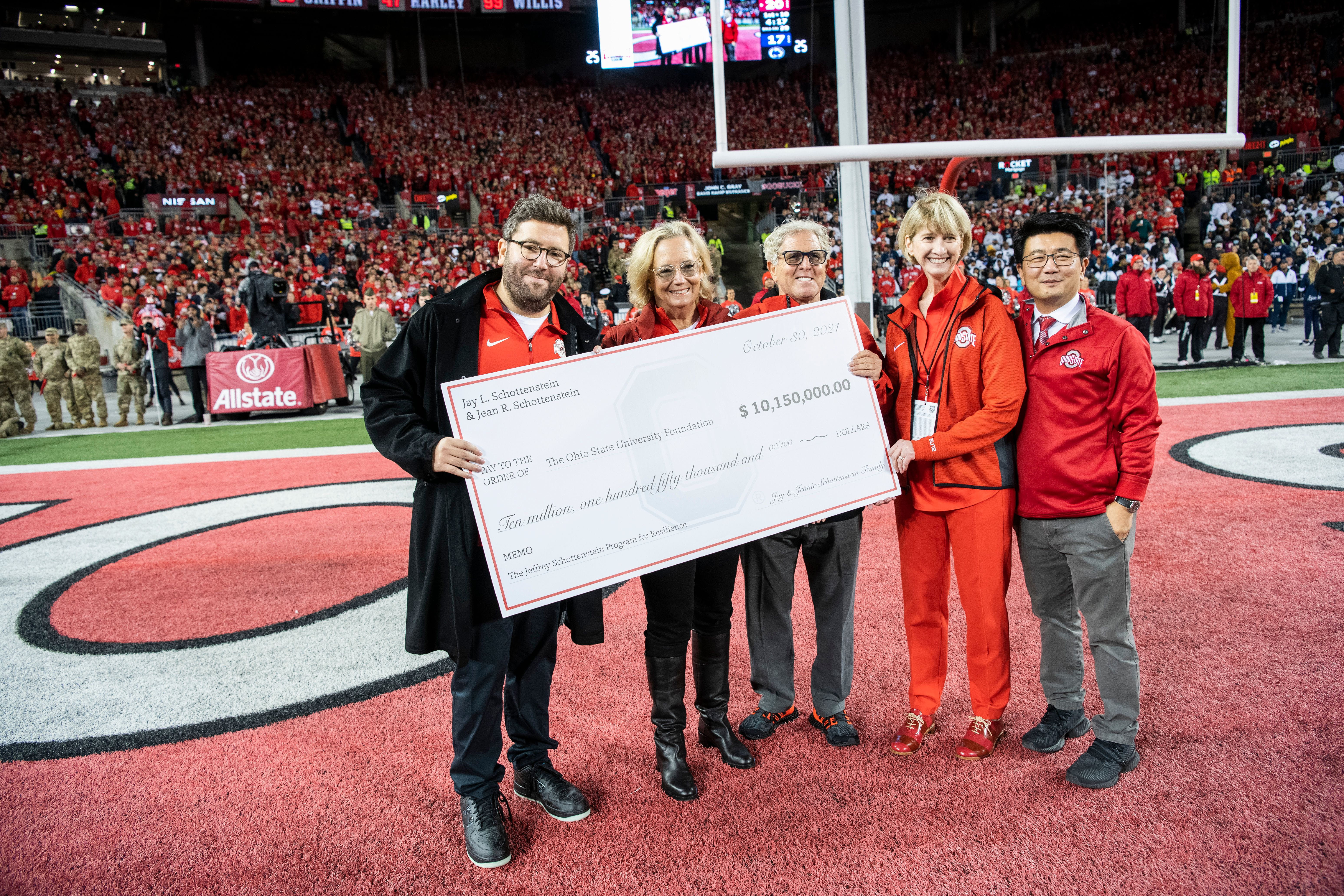 The Schottensteins, President Kristina Johnson and Dr. K. Luan Phan on the field at Ohio Stadium during the Ohio State-Penn State football game.